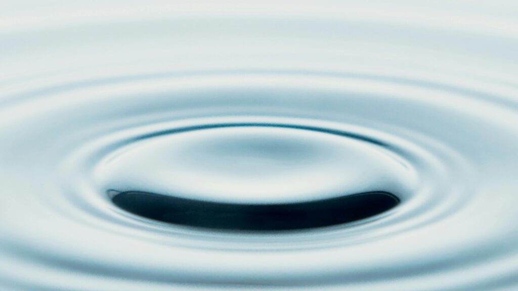 A close-up of a serene water ripple creating a minimalist abstract art piece. Ideal for tranquil designs.